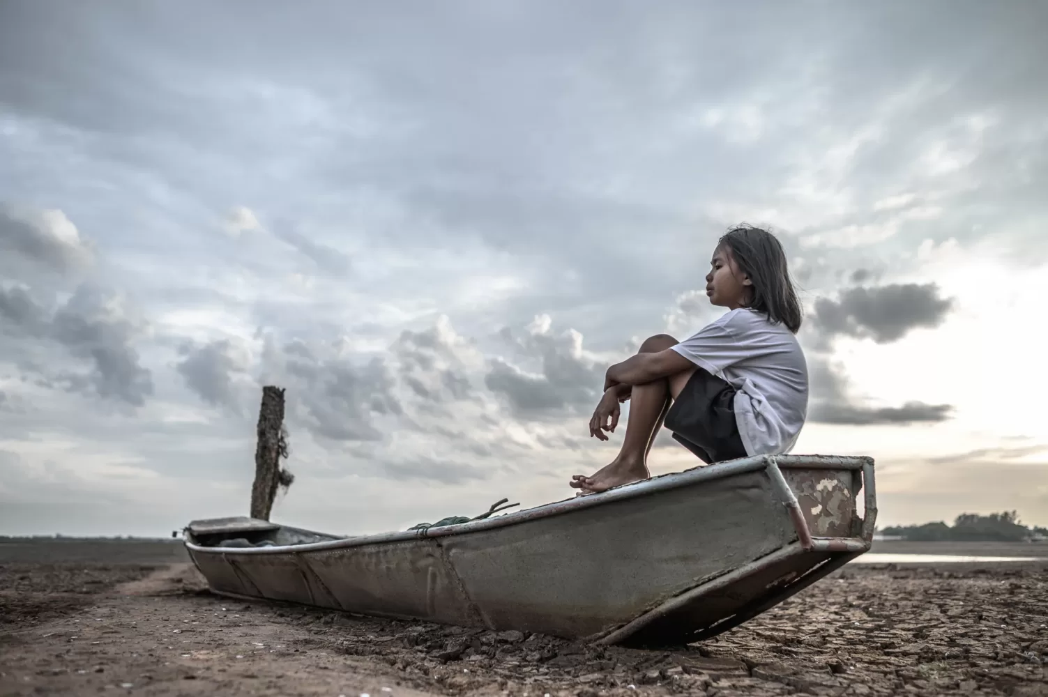 Niña sentada en un rio seco por el fenómeno del niño